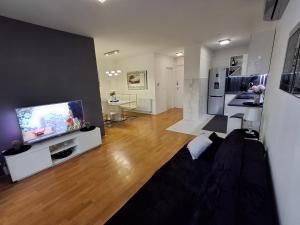 a living room with a flat screen tv and a kitchen at Apartman Tonka in Šibenik