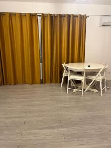 - une table et des chaises dans une chambre dotée de rideaux jaunes dans l'établissement One, à Craiova
