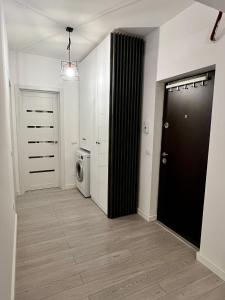 un couloir avec un lave-linge et une porte noire dans l'établissement One, à Craiova