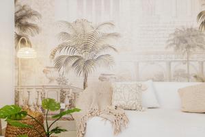 a living room with a white couch and a palm tree mural at 1001 Nights - Luxury 1-BR apartment near Burj in Dubai +36 photos