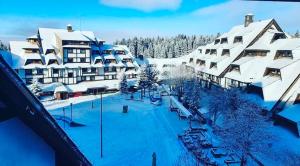 um resort na neve com edifícios cobertos de neve em Vuk & Sofija Apartmani em Kopaonik