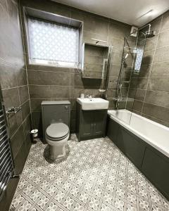 a bathroom with a toilet and a sink and a tub at Balincourt in Bournemouth