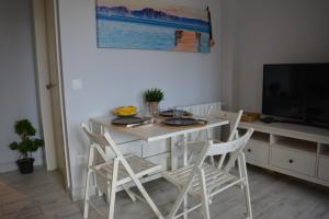 a white dining room table with chairs and a television at La playa in Suances