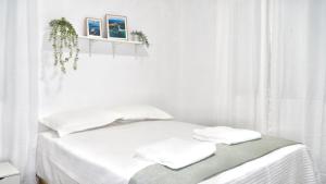 a white bedroom with a bed with white sheets and pillows at Estrella de Mar in Pedernales
