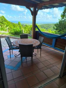 a patio with a table and chairs and a hammock at Concept Kreyol in Sainte-Rose