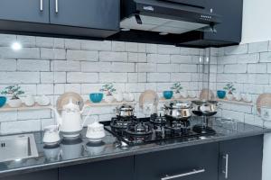 a kitchen counter with a stove with pots and pans at A - Jey Paradise in Mannar