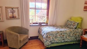 Un dormitorio con una cama y una silla y una ventana. en A2B Eco Farm, Byrne Valley, KZN, en Byrne
