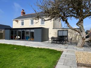 a house with a patio and a tree at Homely Pembrokeshire Farmhouse in Tenby