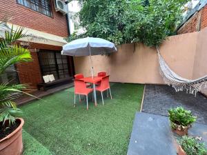 a red table and chairs with an umbrella in a yard at Las Arecas - rucci 61 in Puerto Iguazú