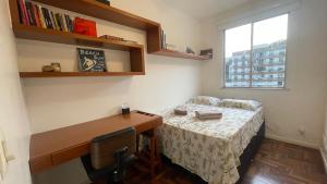 um quarto com uma cama, uma escrivaninha e uma janela em Amplo e iluminado apartamento na Gávea no Rio de Janeiro
