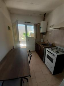 eine Küche mit einem Tisch, einem Herd und einer Arbeitsplatte in der Unterkunft Gotas de Rocio N1 in San Antonio Oeste