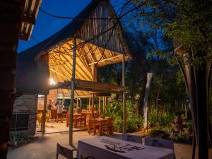 a wooden pavilion with tables and chairs in a garden at Kruger Maroela Lodge in Marloth Park