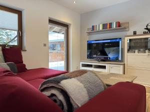 a living room with a red couch and a flat screen tv at Feriendomizil Garber-Bründl in Oberau