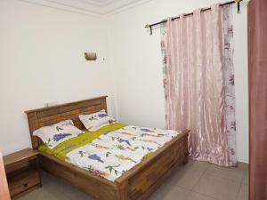 a bedroom with a wooden bed and a curtain at Olympus House Meuble in Yaoundé