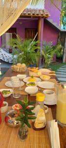a wooden table with plates of food on it at Pousada do Titi in Caraíva