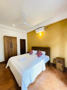 a bedroom with a bed with white sheets and red pillows at Villa Minos in Hikkaduwa