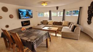 A television and/or entertainment centre at Casa Caledonia - Appartement dans villa avec jardin arboré et piscine à 500 M de la mer