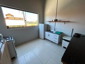 a small kitchen with a refrigerator and a window at Complexo Brisa Ferrugem in Garopaba +12 photos