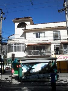 uma pessoa a tirar uma fotografia a um autocarro em frente a um edifício em Apartamento Teresópolis - Centro em Teresópolis
