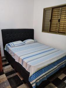 a bed in a bedroom with a black headboard and a window at Rancho Costa in Pereira Barreto