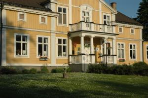 a large yellow house with a porch and a yard at Spånhults Herrgård Hostel in Norrahammar