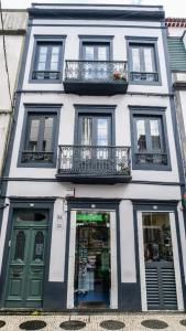 Un edificio alto y blanco con ventanas y balcones. en Cilio House, en Ponta Delgada