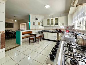 una cucina con mobili bianchi e un tavolo con sedie di Linda casa 5 quartos prox a av cataratas e centro a Foz do Iguaçu