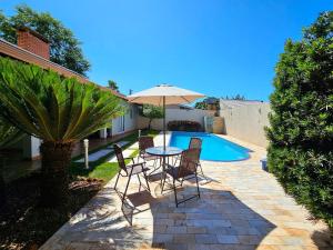 un patio con tavolo e sedie accanto alla piscina di Linda casa 5 quartos prox a av cataratas e centro a Foz do Iguaçu