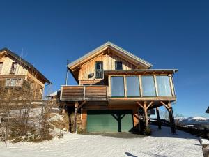 une maison en rondins dans la neige avec un balcon dans l'établissement Wellnesshütte Klippitztörl, à Klippitztorl