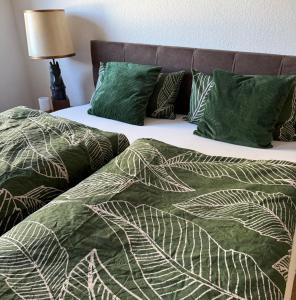 a bed with green and white sheets and pillows at Schöne Ferienwohnung mit kostenlosem Parkplatz in Cottbus