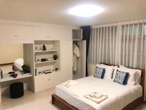 Un dormitorio con una gran cama blanca con almohadas azules. en Breeze House Downtown Chatuchak, Lat Phrao, en Bangkok