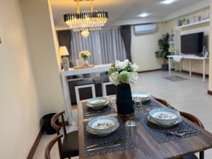 una mesa con platos y un jarrón con flores. en Breeze House Downtown Chatuchak, Lat Phrao, en Bangkok
