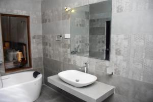 a bathroom with a sink and a mirror and a tub at Shavona Bliss Mirissa in Mirissa