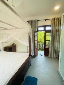 a bedroom with a bed with a mosquito net at Pathum Guest House Midigama in Midigama