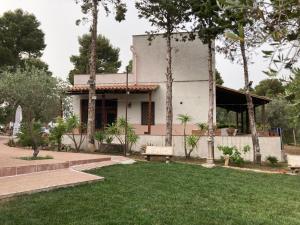 a white house with a lawn in front of it at Noravilla con piscina fra mare e montagne in Mandra Capreria