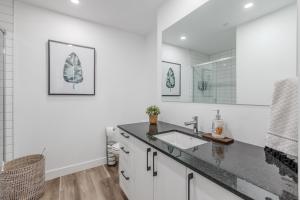 ein weißes Badezimmer mit Waschbecken und Spiegel in der Unterkunft L'Horizon Urbain, Centre Ville, Toit-Terrasse Gym in Québec + 19 Fotos