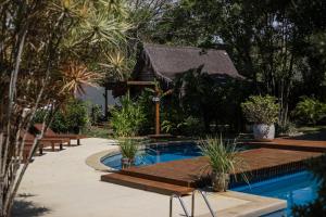 a pool with a wooden deck next to a house at Villa Cozy - Pousada Boutique in Arraial d'Ajuda