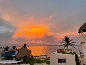 a sunset over the ocean with houses and palm trees at Casa Velero Puerto Morelos in Puerto Morelos