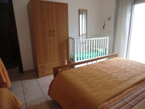 アルカモ・マリーナにあるCase Vacanze C M Windsurfのベッドルーム1室(ベッド1台、ドレッサー、ベビーベッド1台付)