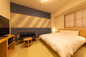 东京Onyado Nono Asakusa Natural Hot Spring的一间卧室配有一张床、一台电视和一把椅子