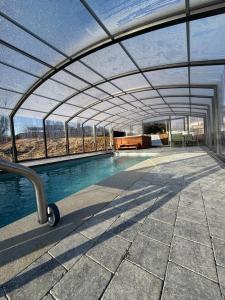 an indoor swimming pool with a retractable roof at la chocolaterie in Roly