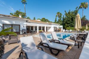 a patio with chairs and a swimming pool at Villa Casa La Concha - Luxury 6 bedroom Villa in Marbella, Beautiful Mountain View, Heated Swimming Pool, 15min walk to Puerto Banus Beaches, Sleeps up to 12 in Marbella
