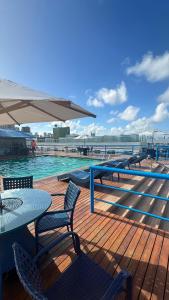 una piscina con mesa, sillas y sombrilla en Victory Flat Tambaú BR, en João Pessoa