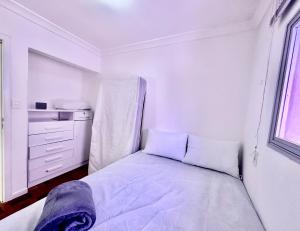 a white bedroom with a bed and a window at João Machado Fortes in Florianópolis
