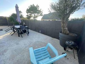 a blue chair sitting next to a tree in a backyard at Jacuzzi privé 500m de la mer in Blainville-sur-Mer