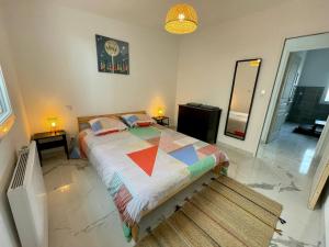 a bedroom with a bed with a colorful quilt on it at Jacuzzi privé 500m de la mer in Blainville-sur-Mer