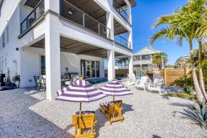 deux parasols et chaises devant un bâtiment dans l'établissement Sunset Oasis - Luxury Pool Home - 350 Feet to the Beach, à New Smyrna Beach