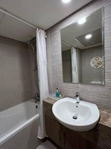 a bathroom with a sink and a tub and a mirror at Cozy Studio - Your Comfort First! in Abu Dhabi
