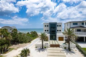 a house on the beach with palm trees at Sunrise Hideaway - Ocean View Luxury Pool Home - 350 Feet to the Beach in New Smyrna Beach