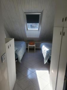 Un dormitorio abuhardillado con dos camas y una ventana. en Casa 2112, en Sestola